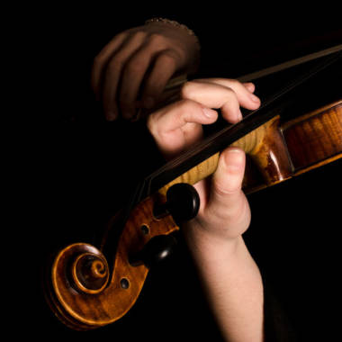 Female hands play a violin on black